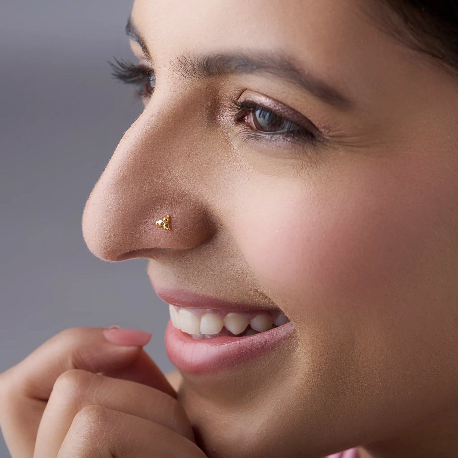 Woman wearing tiny 18k gold nose pin showcasing elegant minimal daily wear look