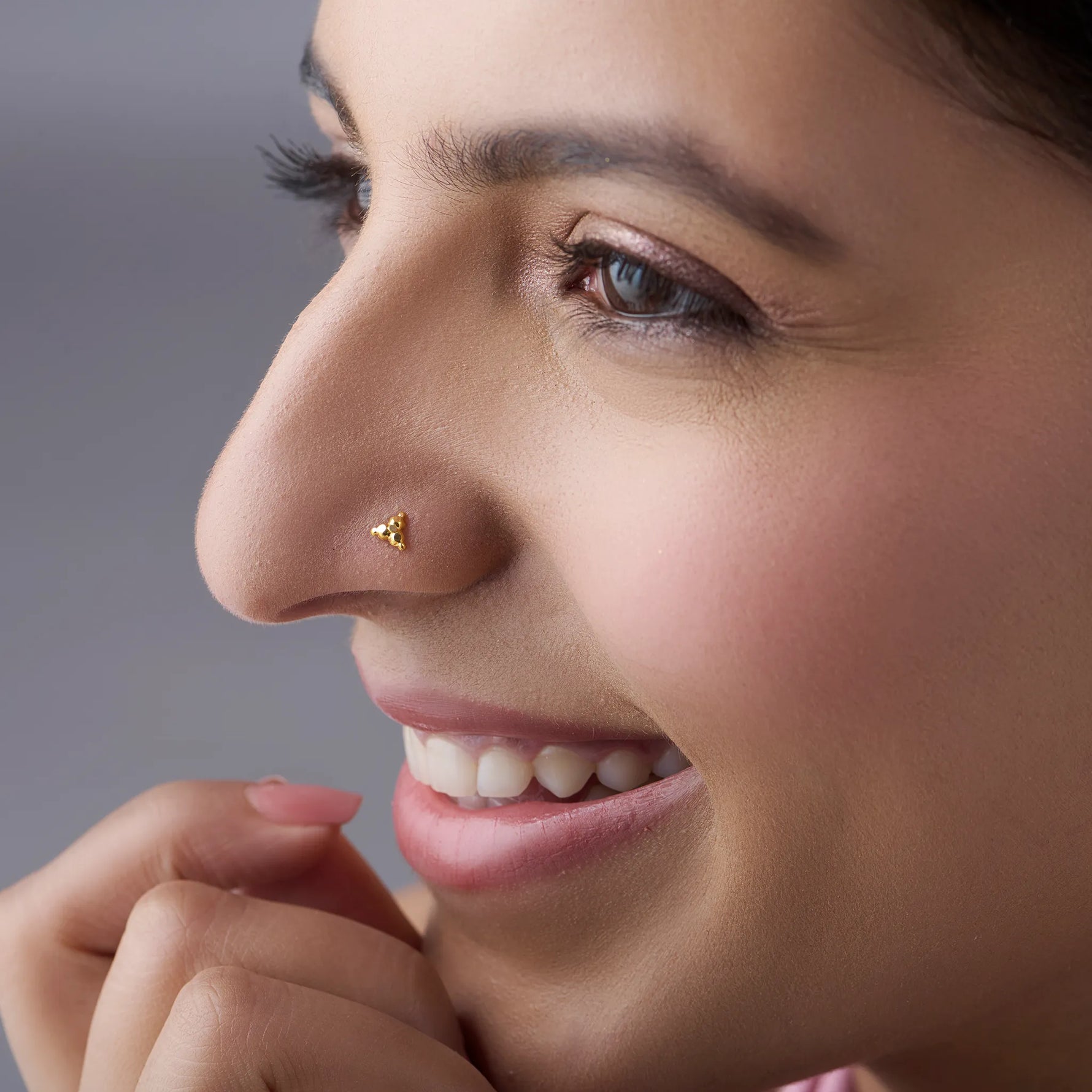 Woman wearing tiny 18k gold nose pin showcasing elegant minimal daily wear look