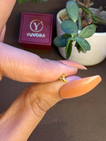 Hand holding small 18k gold nose pin with Yuvora packaging in background