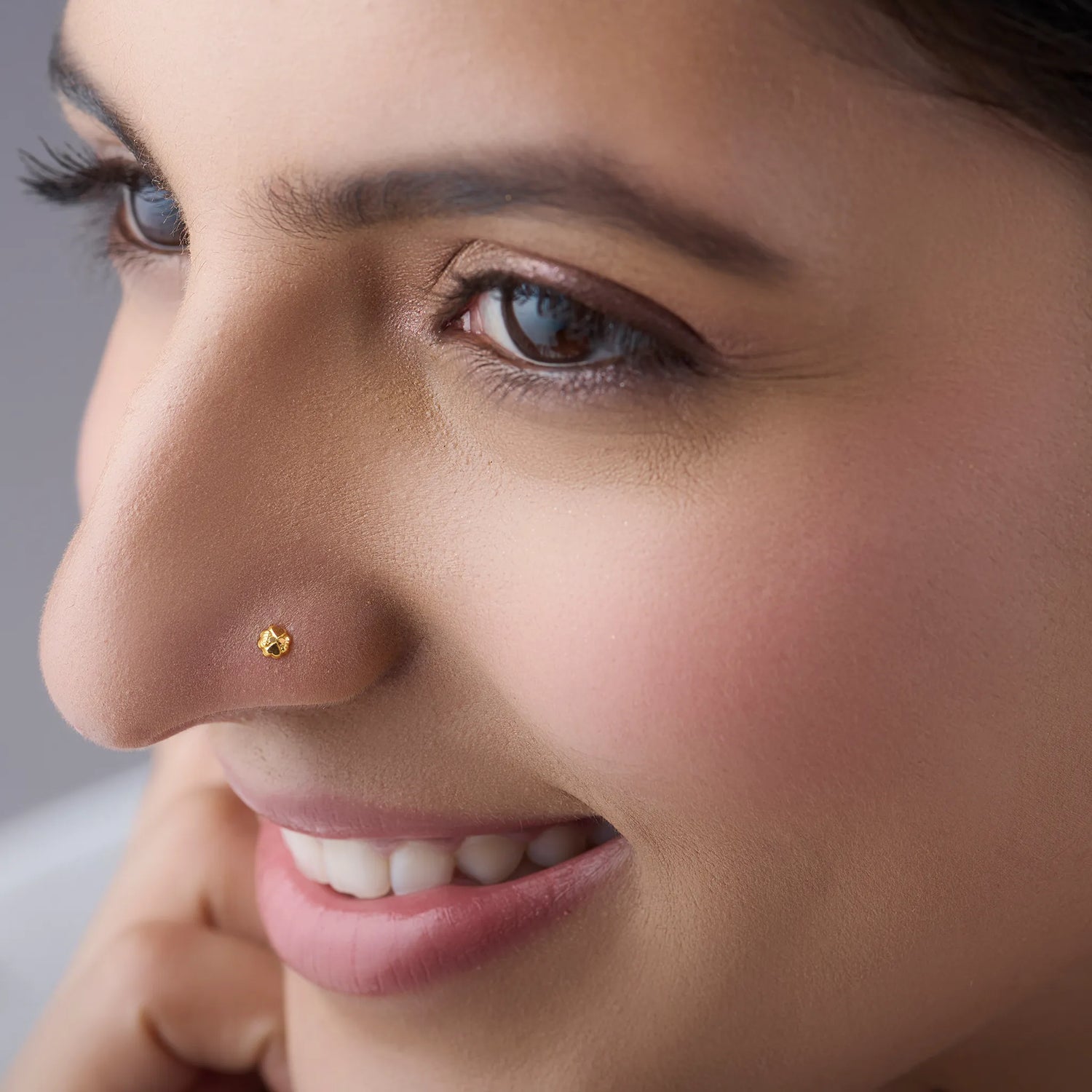Close up of a woman wearing a small gold nose pin highlighting a minimal elegant everyday look
