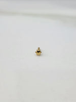 Slight angled view of a small 18K gold nose pin on a white surface highlighting its lightweight structure and polished finish