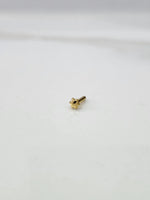 Front view of a tiny 18K gold nose pin placed on a white background showing its compact size and fine detailing