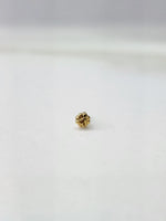 Side view of a delicate gold nose pin on a white surface showing its lightweight structure and fine detailing