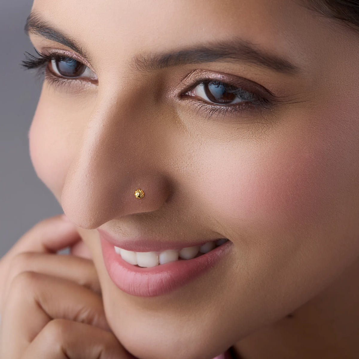 Woman wearing a small gold nose pin showcasing a graceful close up profile and natural everyday elegance