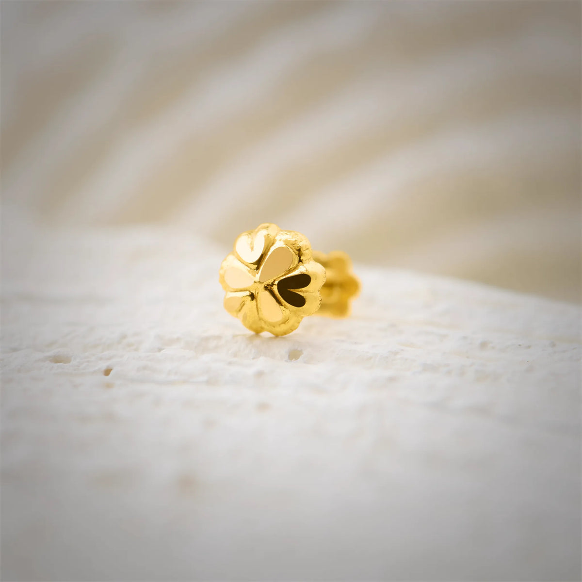 Close up of elegant floral gold nose pin design crafted in 18k yellow gold featuring soft petal detailing for women