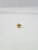 Front view of a small gold nose pin placed on a white background highlighting delicate detailing
