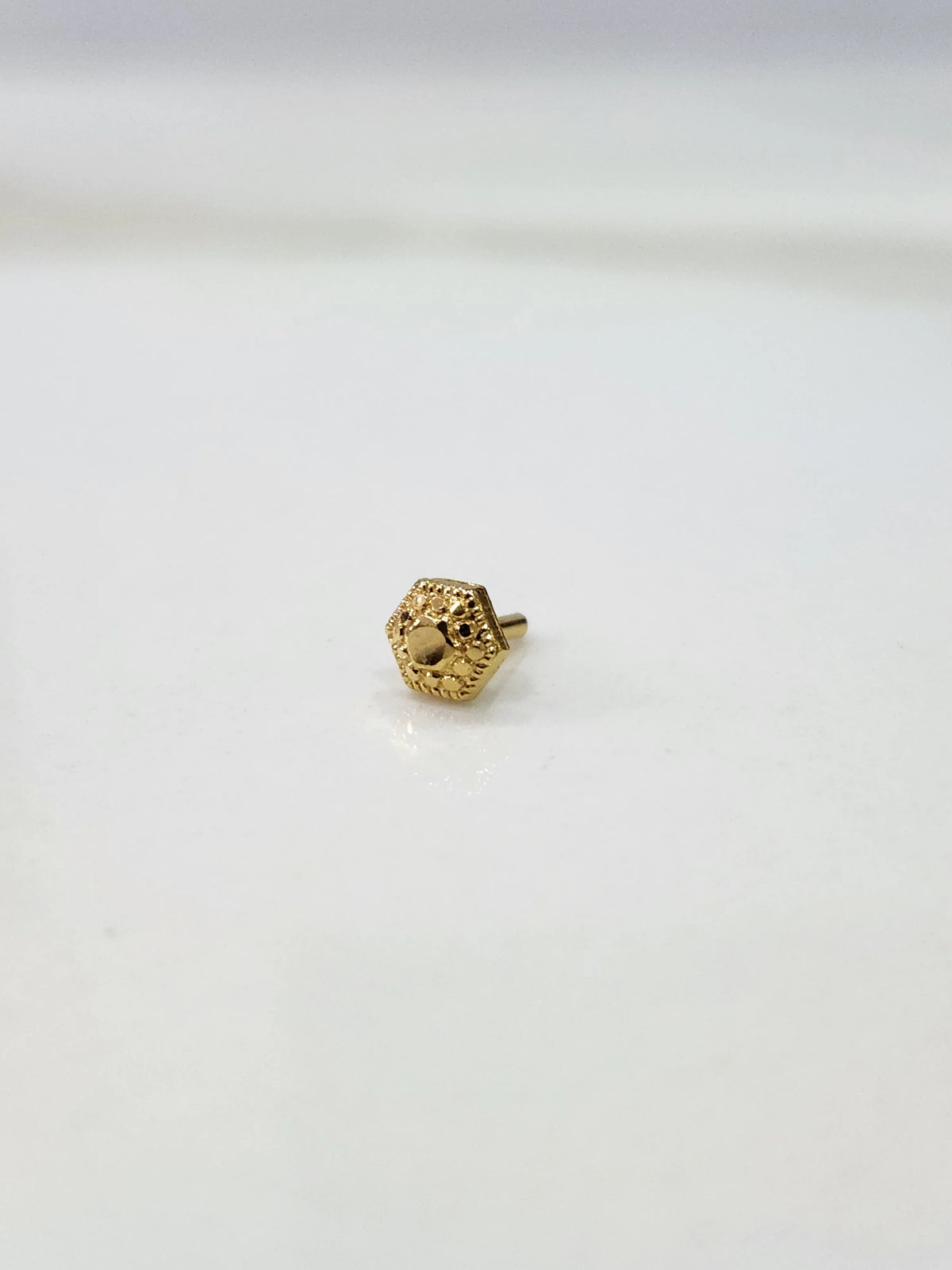 Small 18K Nose Pin Gold placed on a white surface showing fine craftsmanship