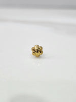 Slight angled close up of a delicate gold nose pin on a white surface showing fine detailing and compact size