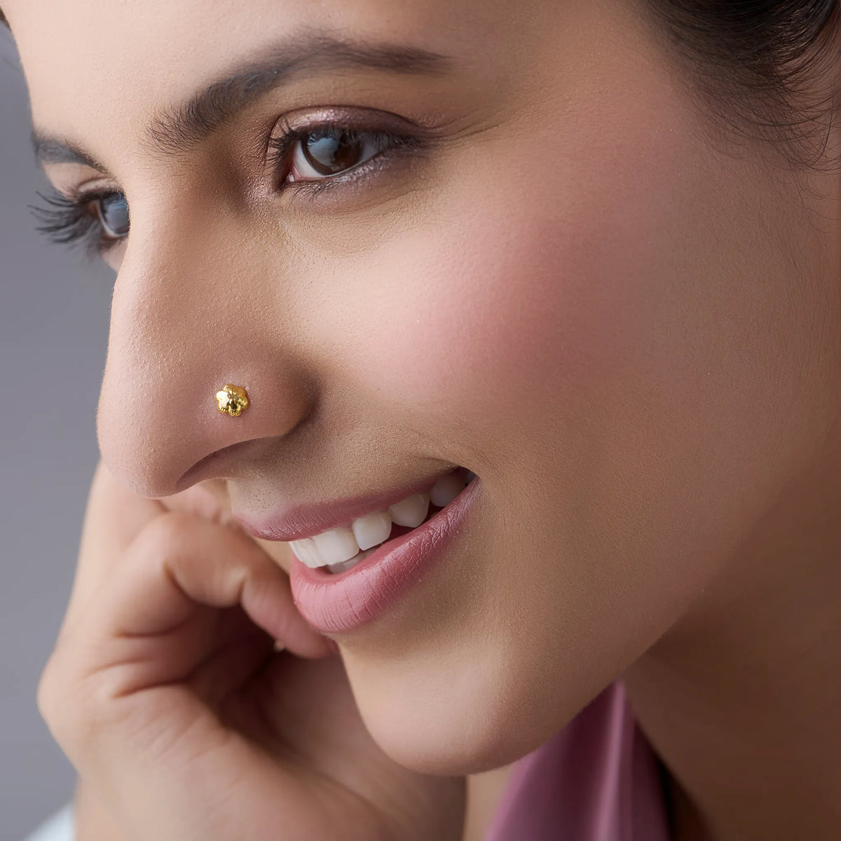 Woman wearing a small 18K gold nose pin showcasing a soft elegant everyday look
