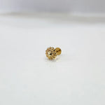 Small floral 18K nose pin gold placed on a white surface capturing its fine craftsmanship