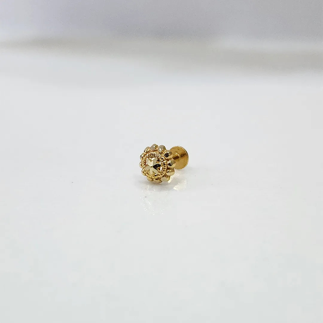 Small floral 18K nose pin gold placed on a white surface capturing its fine craftsmanship
