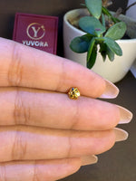 Hand holding a tiny 18K nose pin gold near a Yuvora box showing its small wearable size
