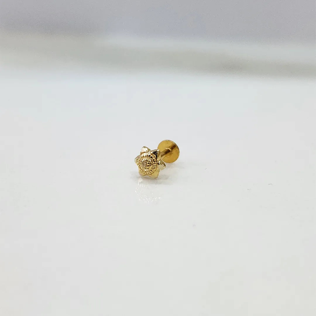 Close-up view of star motif 18K nose pin gold on a white surface displaying its fine detailing