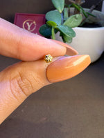 Hand holding a tiny 18K nose pin gold near a Yuvora box showing its compact size and fine craftsmanship