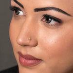 Side profile of a woman wearing a tiny 18K nose pin gold showing its subtle and refined appearance