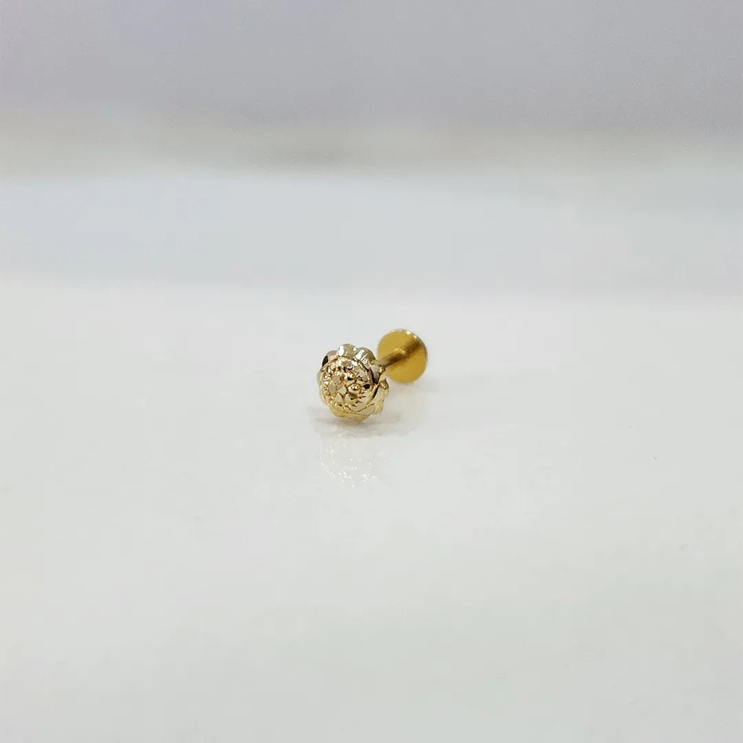 Tiny 18K nose pin gold photographed on a smooth white surface showing its polished finish