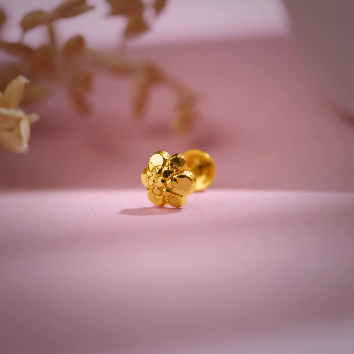 Floral cluster 18K nose pin gold placed on a soft pink backdrop highlighting its intricate handcrafted detailing
