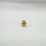 Small spherical 18K nose pin gold on a clean surface capturing its reflective handcrafted detailing