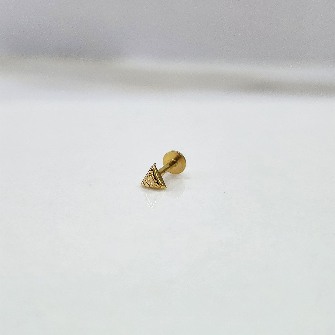 Small triangle 18K nose pin gold displayed on a white surface showcasing its tiny, sleek craftsmanship