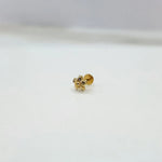 Small floral 18K nose pin gold placed on a white surface for clear visibility of the fine design
