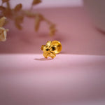 Floral 18K nose pin gold photographed on a soft pink background showcasing its elegant handcrafted detailing