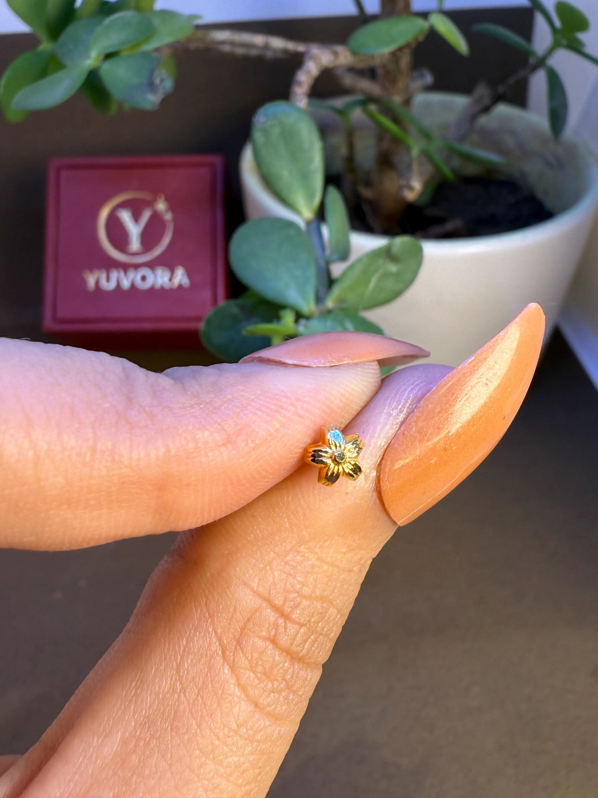 Floral 18K nose pin gold held on fingertips showing its tiny and delicate craftsmanship