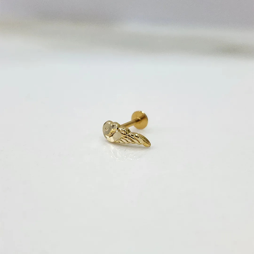 Small 18K nose pin gold placed on a white surface highlighting fine detailing