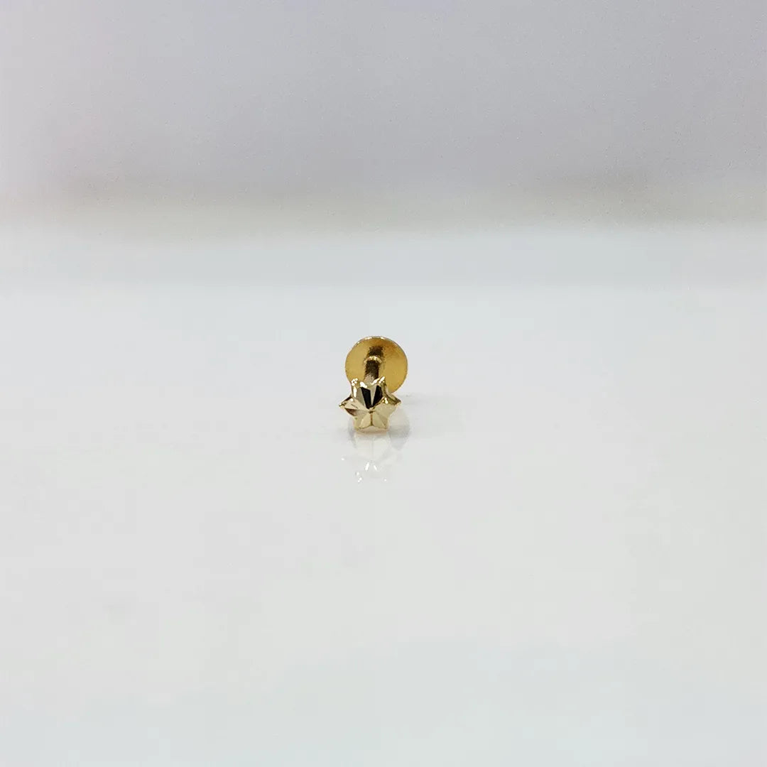Close-up of a small gold star nose pin placed on a white background for clarity