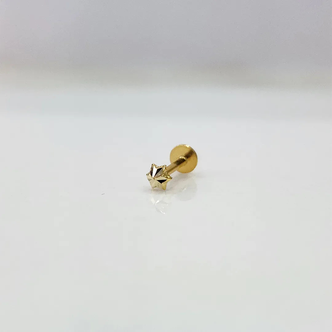 Tiny gold star nose pin on a white surface showing delicate detailing