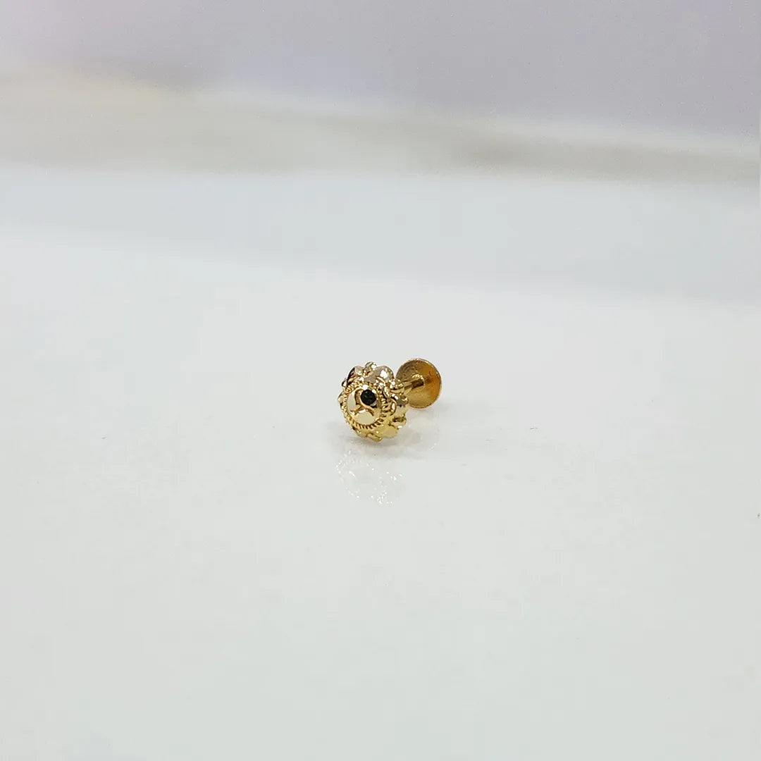 Small gold nose pin on a white surface showing delicate detailing