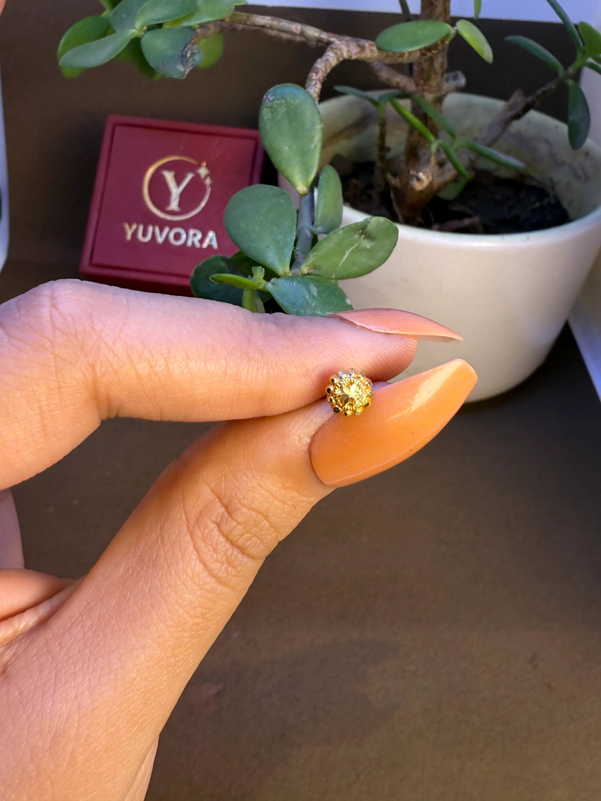 Hand holding a small gold nose pin to display its size and craftsmanship