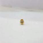 Small gold nose pin on a white surface highlighting its intricate craftsmanship