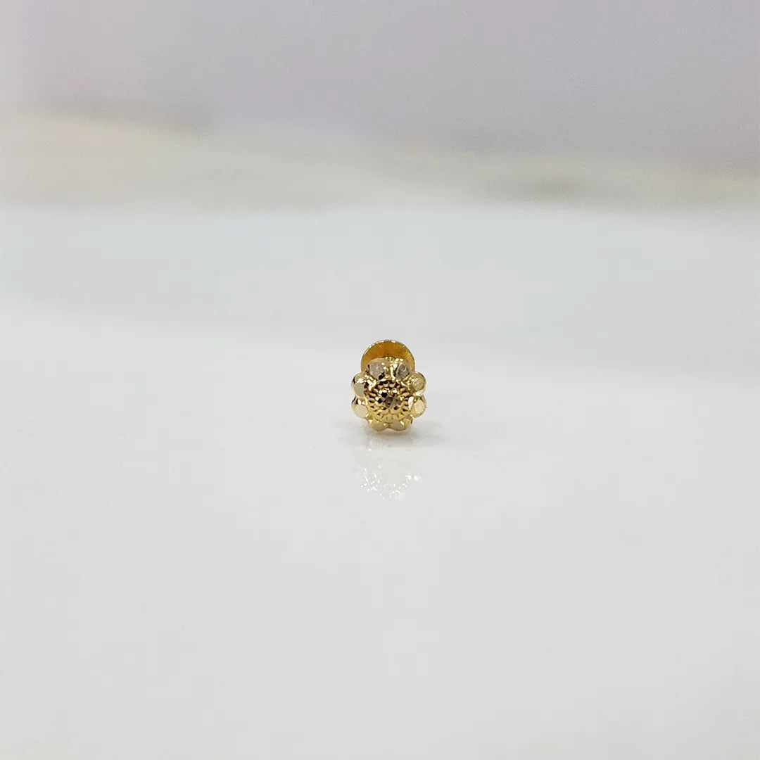 Small gold nose pin on a white surface highlighting its intricate craftsmanship