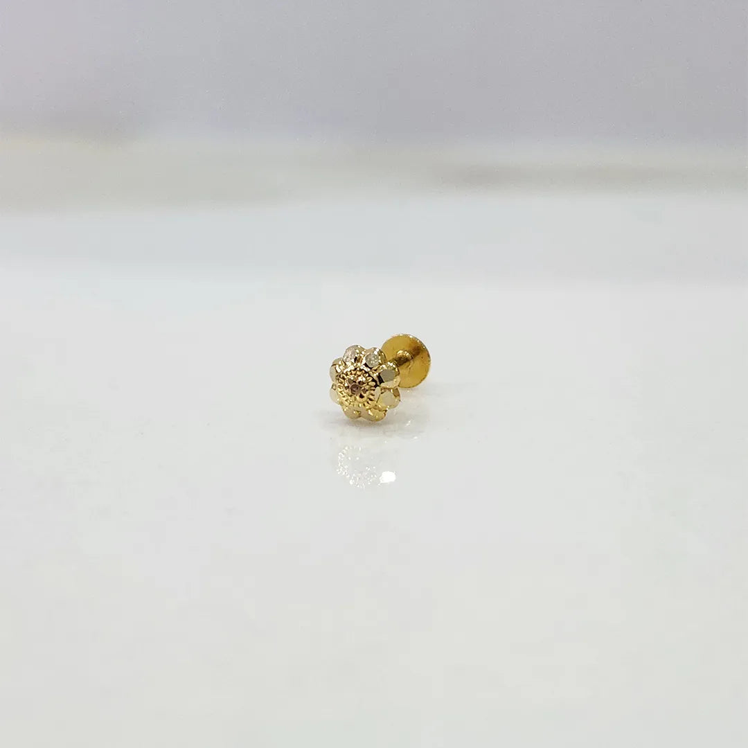 Close-up of delicate gold nose pin placed on a white marble-like background