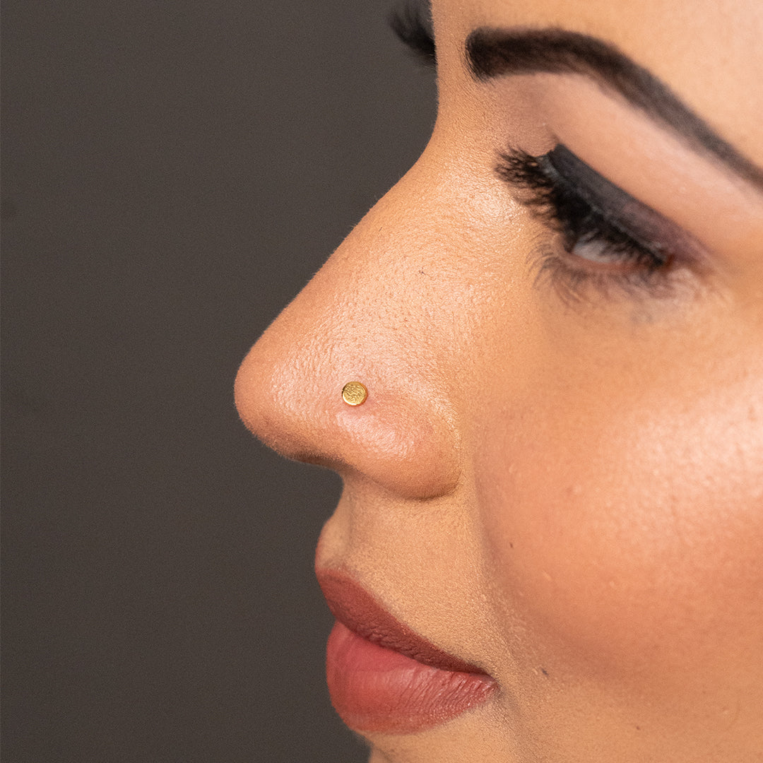 Woman wearing small round gold nose pin showing elegant and simple everyday look