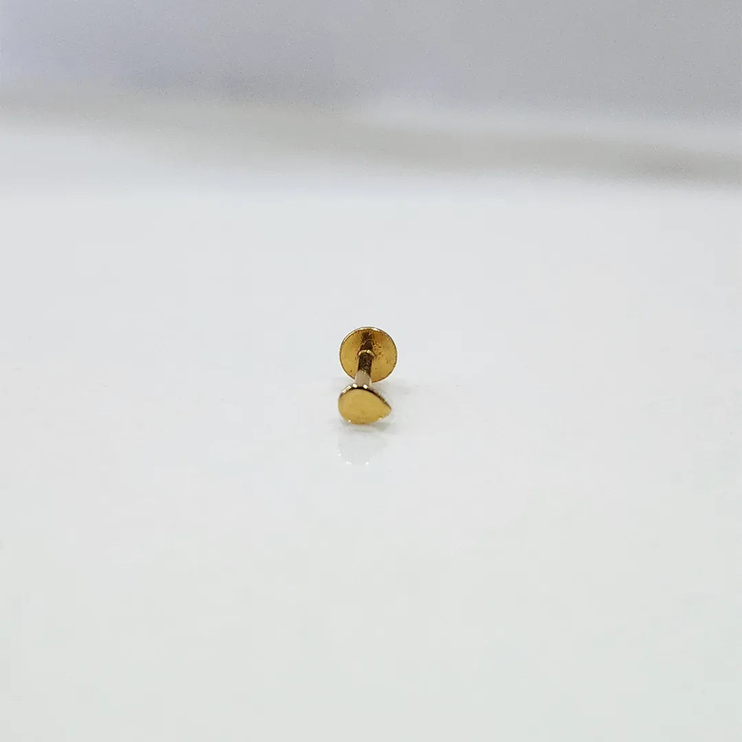 Front view of a small plain 18K gold nose pin on a white surface highlighting its minimal circular design