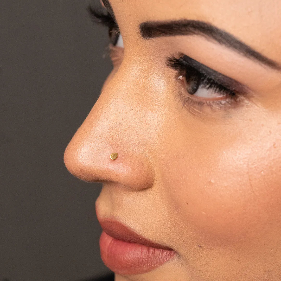 Side profile view of a woman wearing a simple 18K gold nose pin showing a clean and classic look