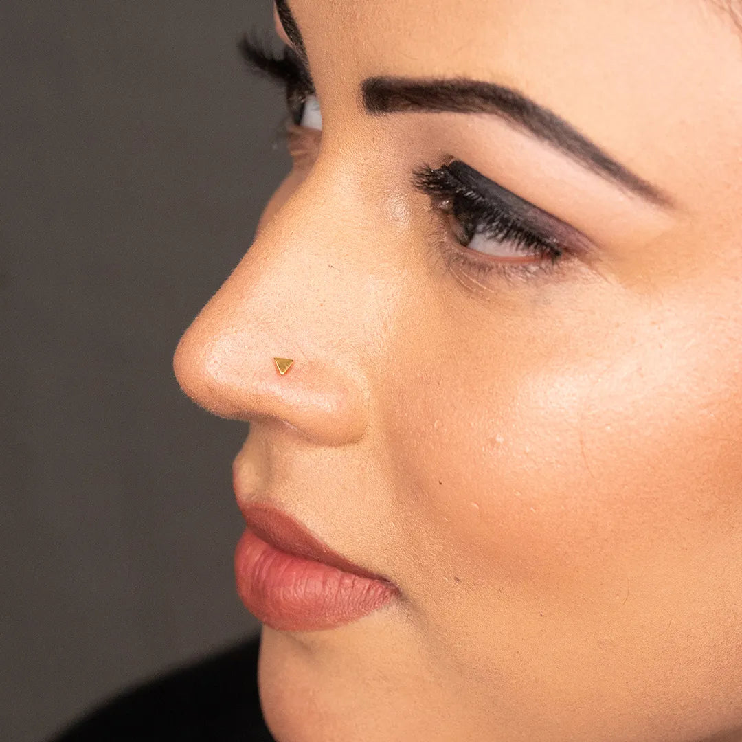 Side profile of woman wearing triangle gold nose pin highlighting sleek and contemporary look
