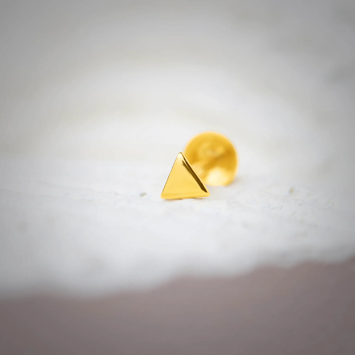 Minimal triangle gold nose pin design crafted in 18k yellow gold with smooth polished finish on white background
