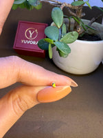 Hand holding a tiny 18K nose pin gold near a Yuvora box showing its small wearable size