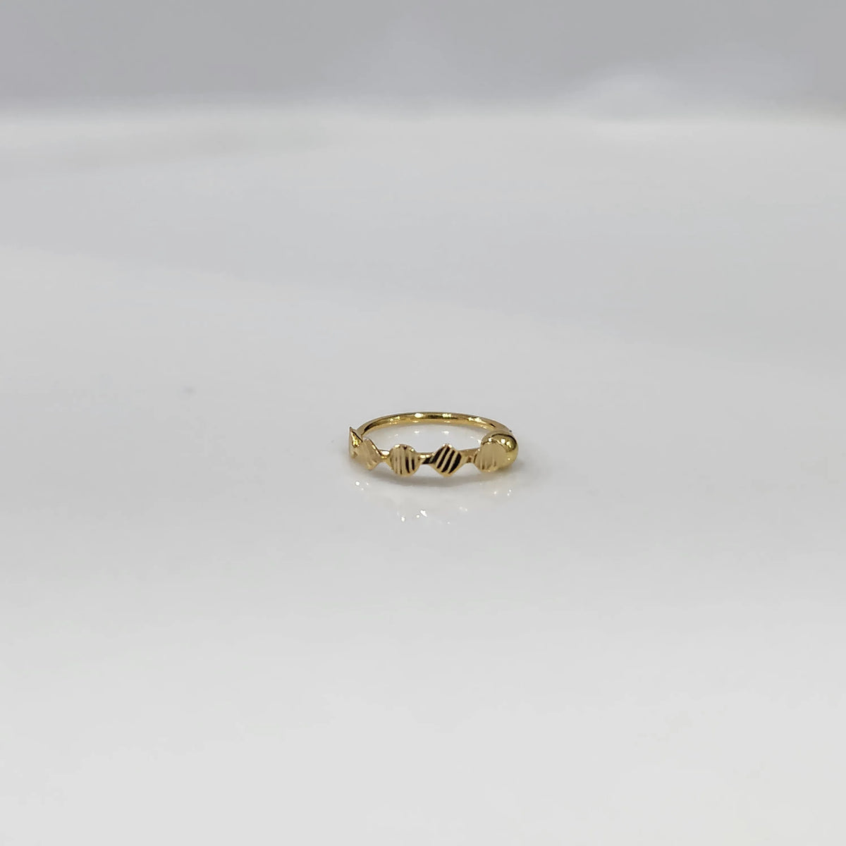 Top view of a petite 18K gold nose ring placed flat on a clean white surface
