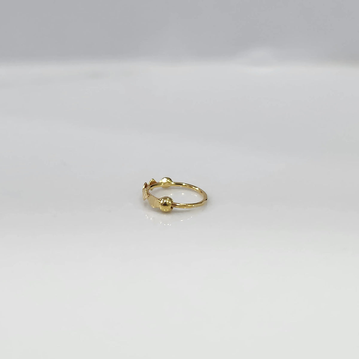 Side angle view of the lightweight gold nose ring on a white background emphasizing its slim profile