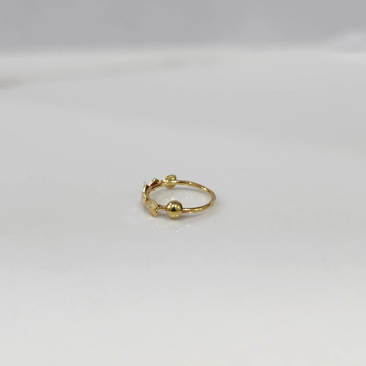Side angle view of delicate zigzag gold nose ring on a white background showing the opening and fit
