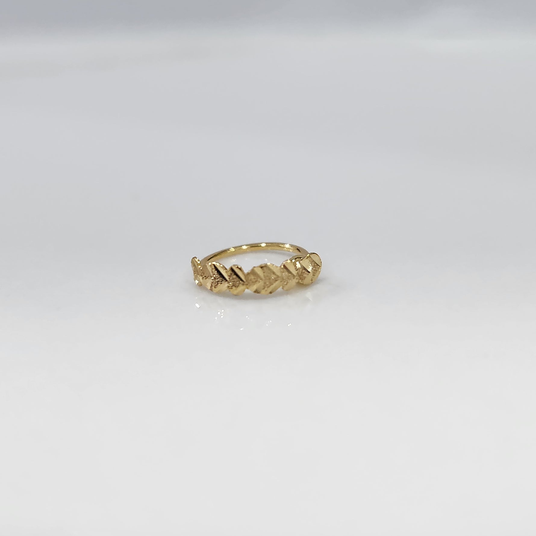 Top view of small twisted design gold nose ring placed on a clean white surface highlighting detailing