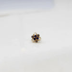 Front view of a small stone gold nose pin on a white background showing the symmetrical floral setting