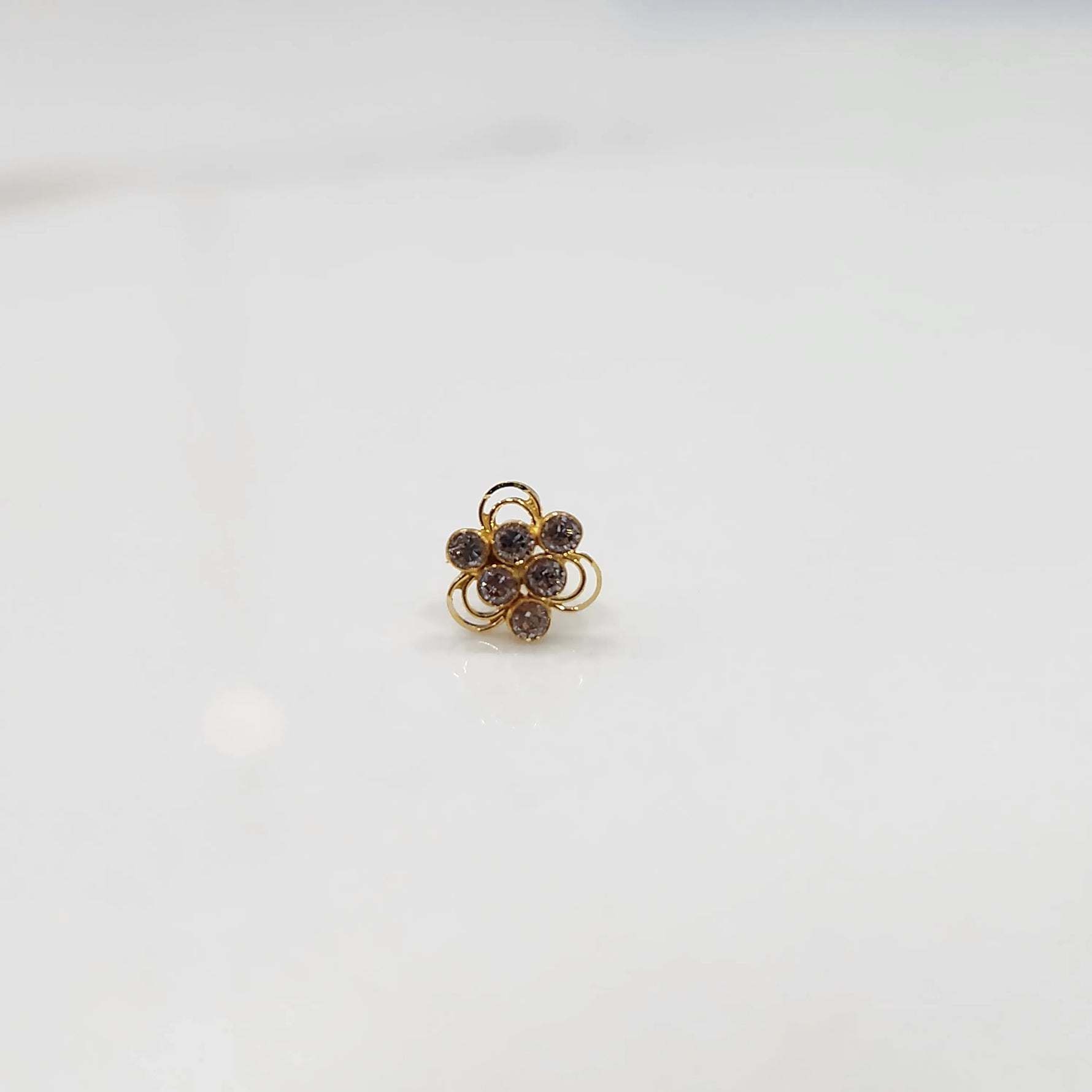 Top view of the floral stone gold nose pin highlighting the central stone and surrounding accents