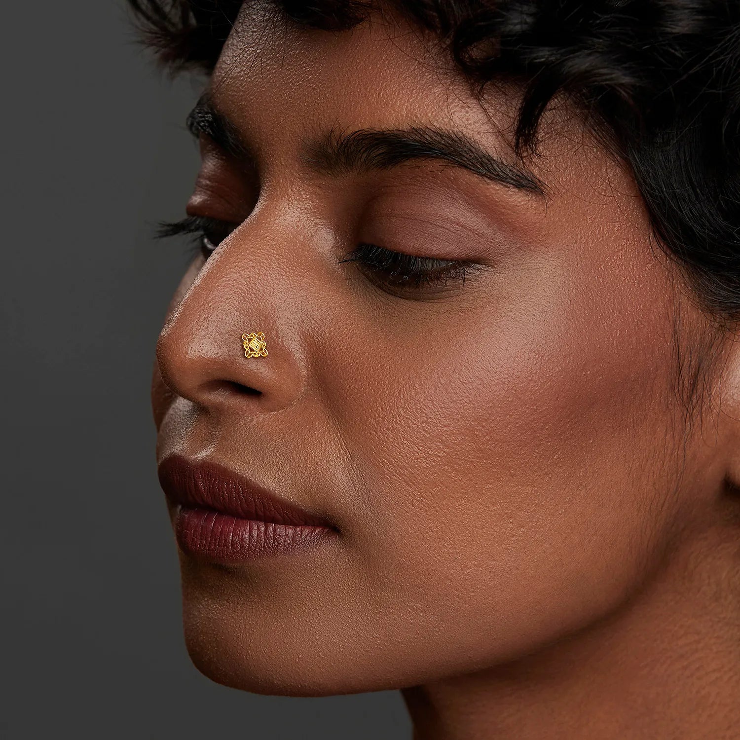 Lifestyle side profile of a woman wearing a delicate 18K gold nose pin on her nose