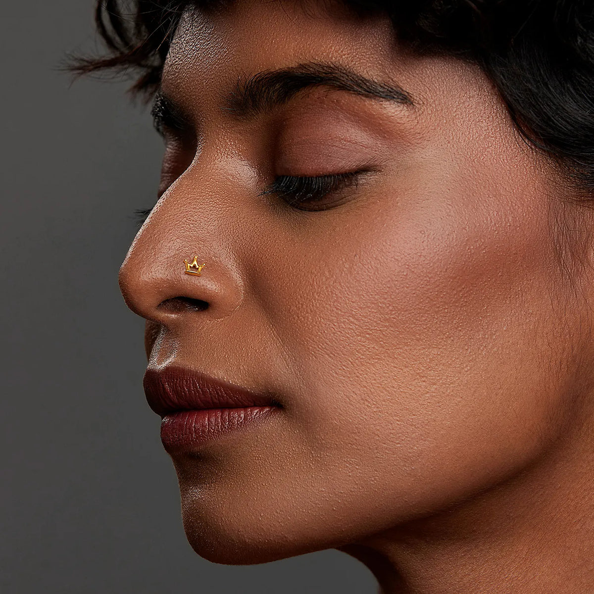 Side profile lifestyle image of a woman wearing a delicate gold nose pin showing an elegant modern look