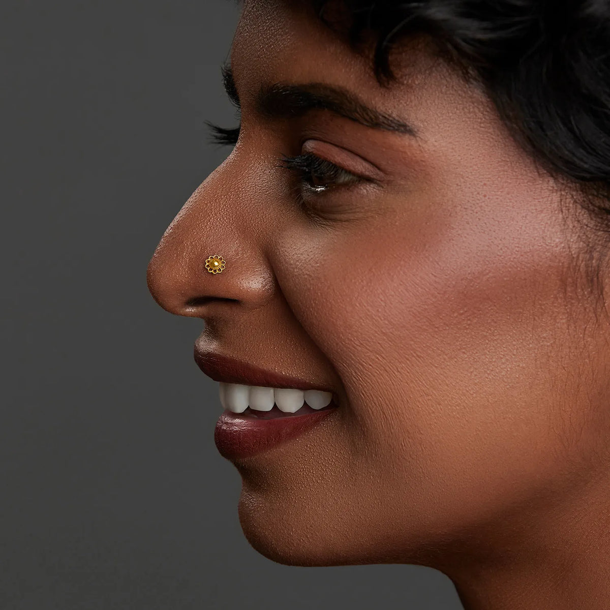Side profile of a woman wearing a small 18K gold nose pin showcasing an elegant and natural look