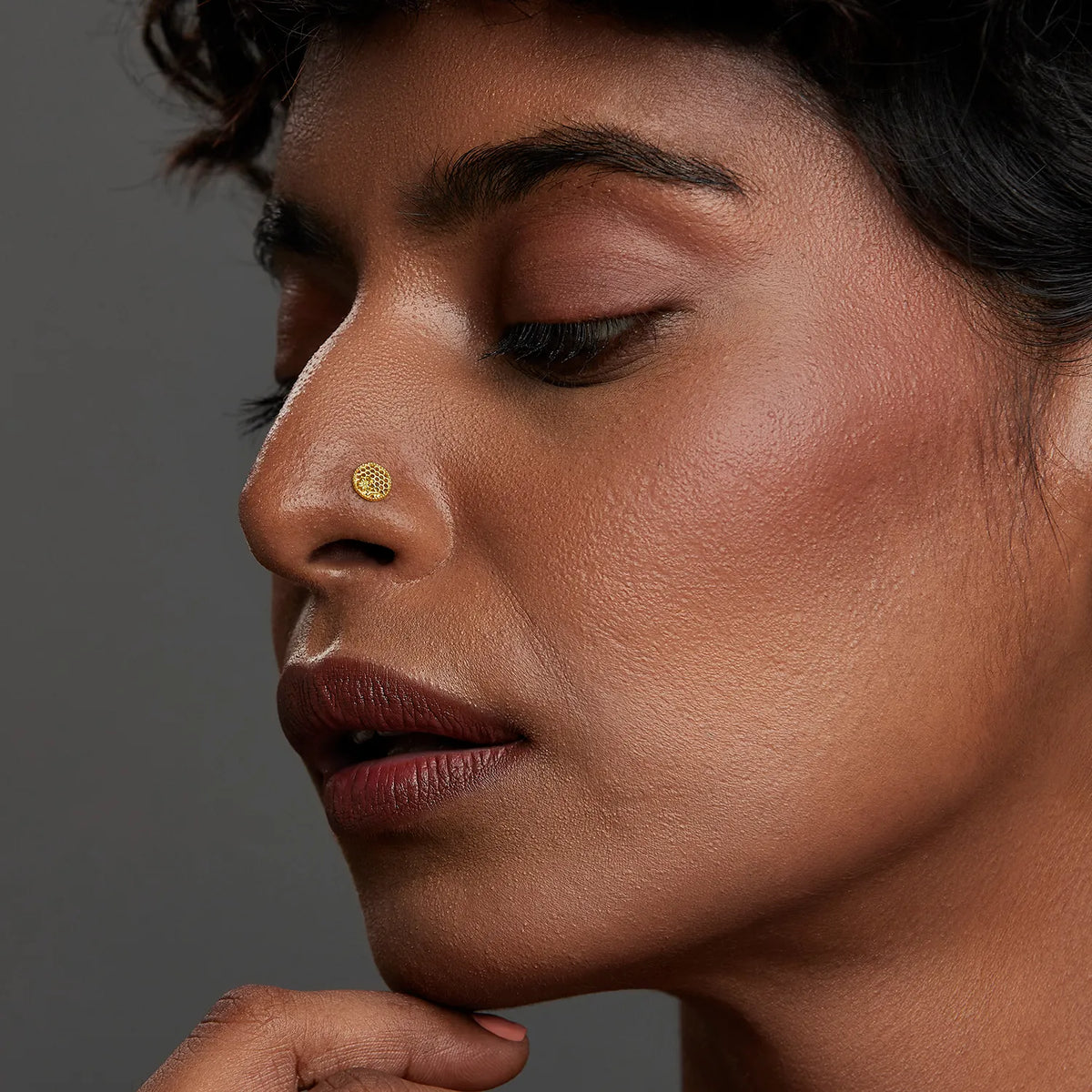 Woman wearing a minimal round 18K gold nose pin shown in side profile highlighting a subtle everyday jewellery look